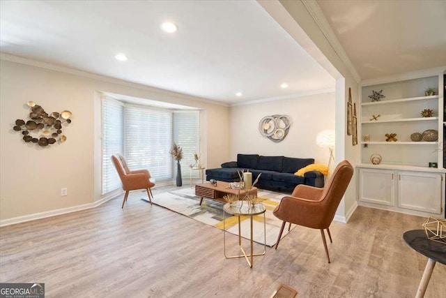 living area featuring light wood-style floors, baseboards, and crown molding