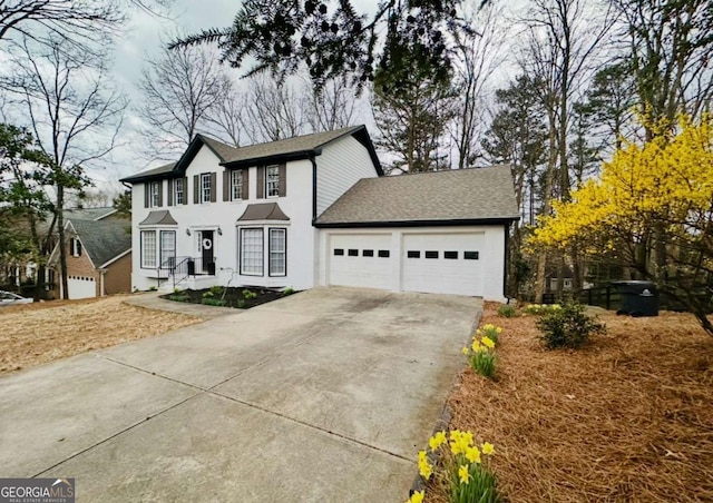 colonial-style house with driveway, a shingled roof, and an attached garage