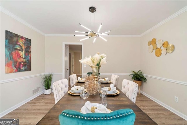 dining area featuring visible vents, ornamental molding, a notable chandelier, and wood finished floors