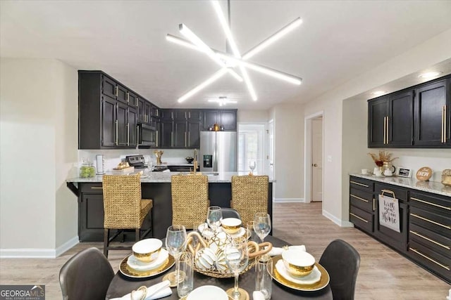 kitchen featuring stainless steel appliances, a peninsula, light wood-style flooring, and baseboards