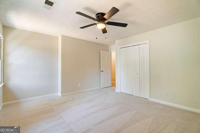 unfurnished bedroom featuring ceiling fan, light carpet, visible vents, baseboards, and a closet