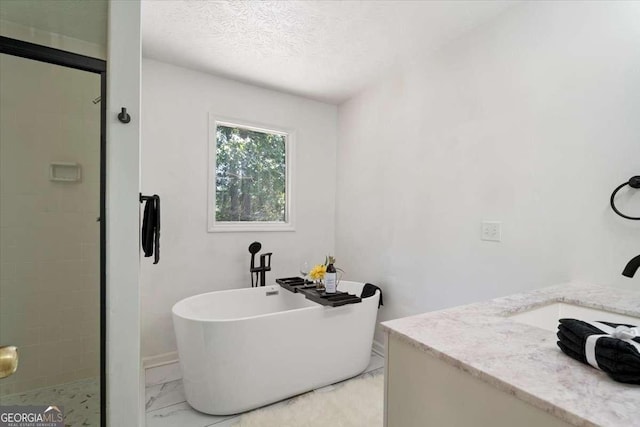 full bath with marble finish floor, a freestanding tub, a textured ceiling, and a shower stall