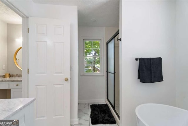 bathroom featuring marble finish floor, a textured ceiling, vanity, a freestanding tub, and a shower stall