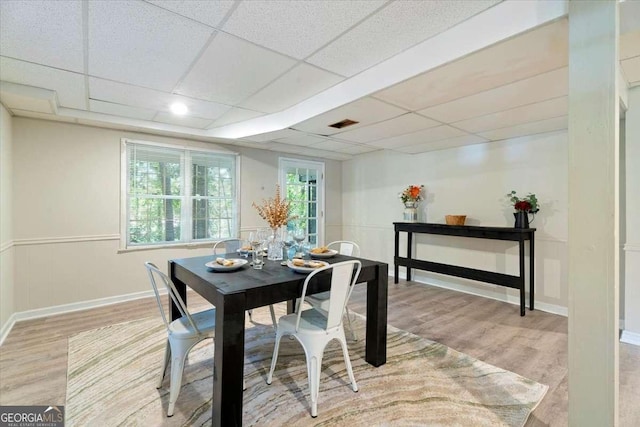 dining room with visible vents, wainscoting, a drop ceiling, and light wood-style flooring