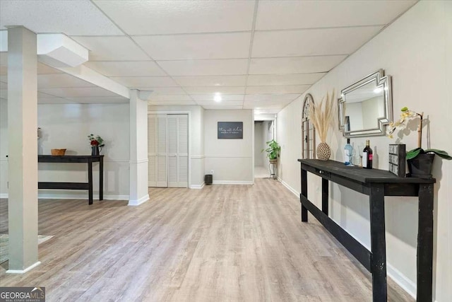 interior space featuring a paneled ceiling, baseboards, and wood finished floors