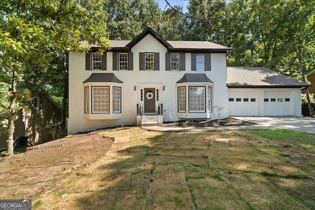 colonial inspired home featuring a garage, driveway, and a front yard