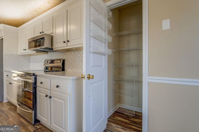 kitchen with decorative backsplash, white cabinets, dark wood-style floors, appliances with stainless steel finishes, and light countertops