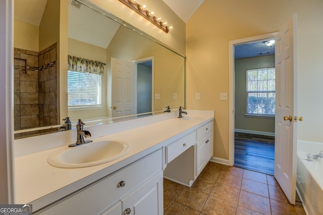 bathroom featuring lofted ceiling, tile patterned flooring, a sink, and a bath