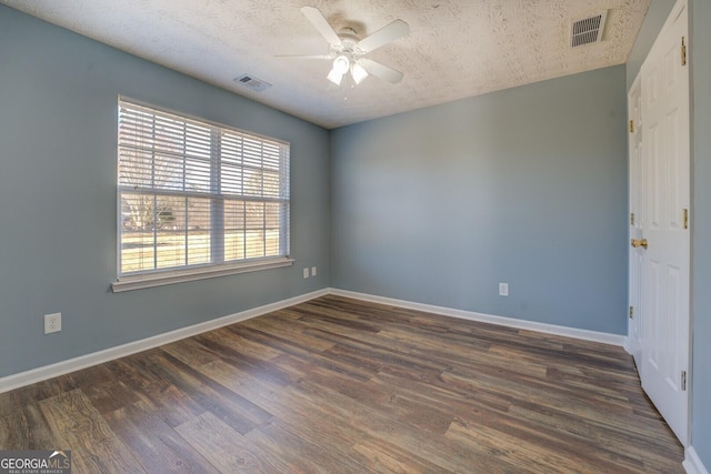 unfurnished room featuring dark wood finished floors, visible vents, and baseboards