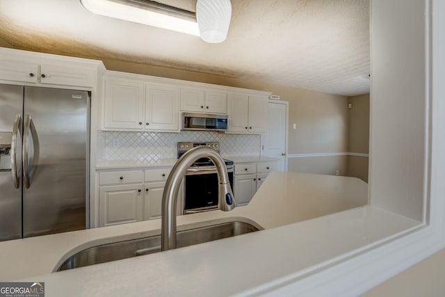 kitchen featuring stainless steel appliances, tasteful backsplash, light countertops, and white cabinets