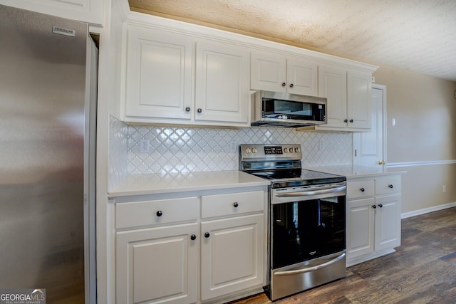 kitchen with dark wood-style floors, stainless steel appliances, light countertops, white cabinetry, and backsplash