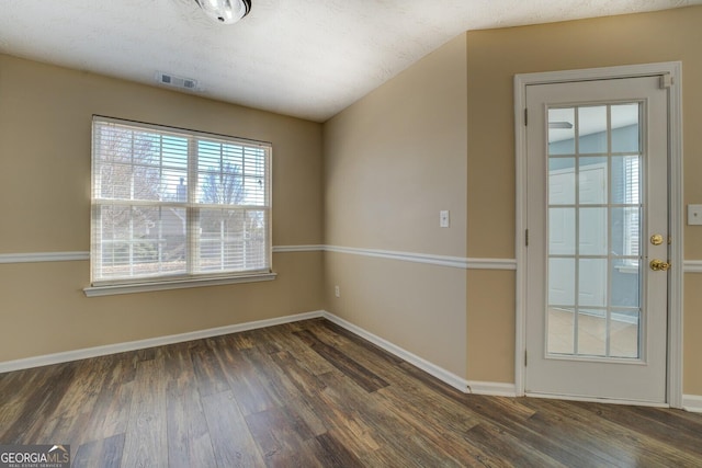 spare room featuring baseboards, visible vents, and wood finished floors