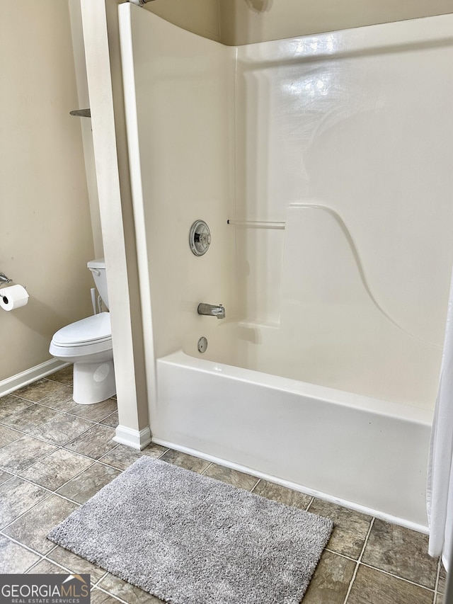 bathroom featuring baseboards, shower / bathing tub combination, toilet, and tile patterned floors