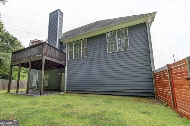 back of property featuring a yard, fence, and a wooden deck