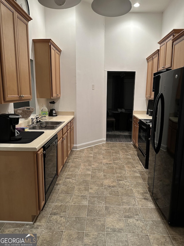 kitchen featuring black appliances, baseboards, light countertops, and a sink