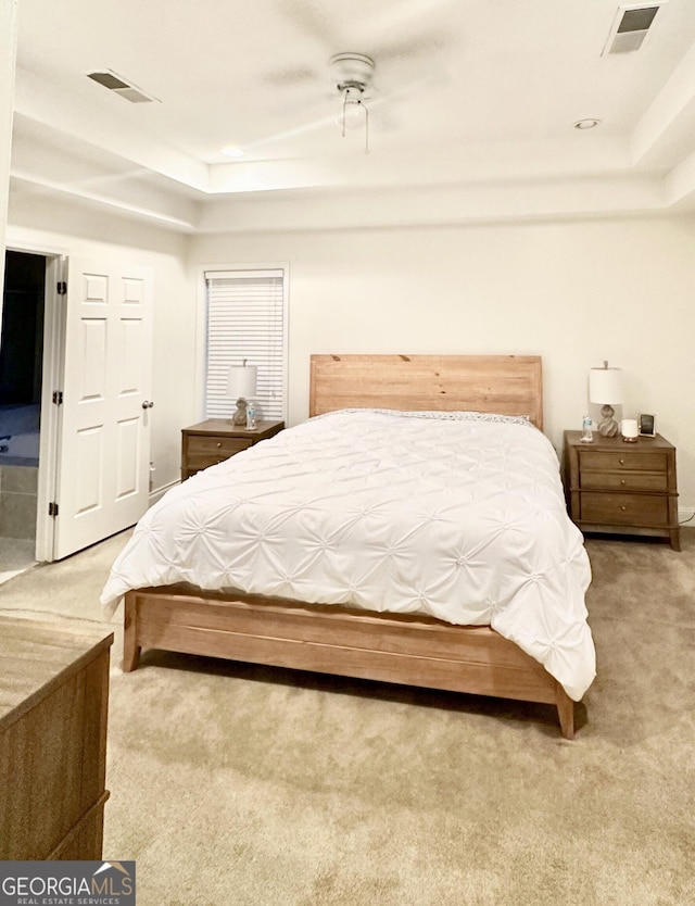 bedroom with a tray ceiling, carpet, and visible vents