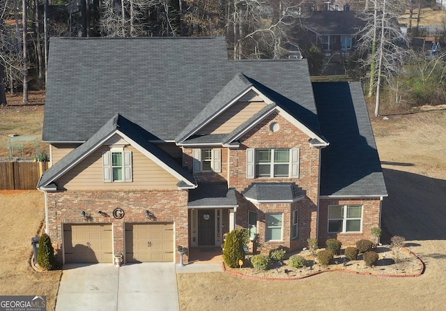 craftsman-style house featuring a garage, concrete driveway, brick siding, and fence