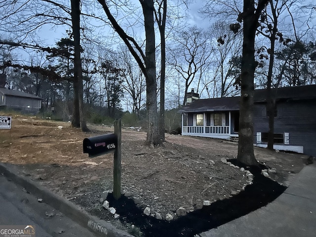 view of side of home featuring driveway, a porch, and a chimney