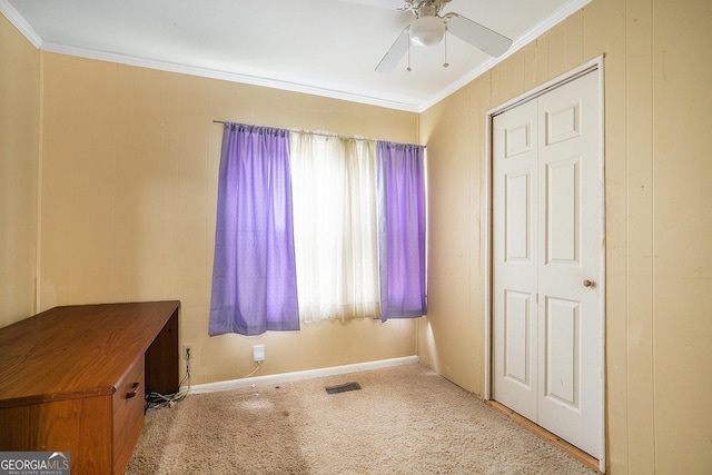 unfurnished bedroom featuring carpet, visible vents, ornamental molding, a ceiling fan, and baseboards