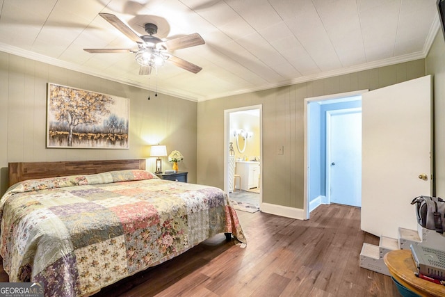 bedroom with wood finished floors, a ceiling fan, baseboards, ensuite bath, and crown molding