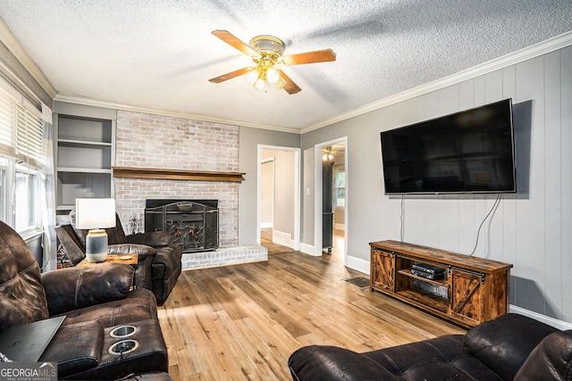 living room featuring crown molding, built in shelves, a textured ceiling, and wood finished floors