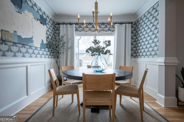 dining area featuring a decorative wall, crown molding, and wood finished floors