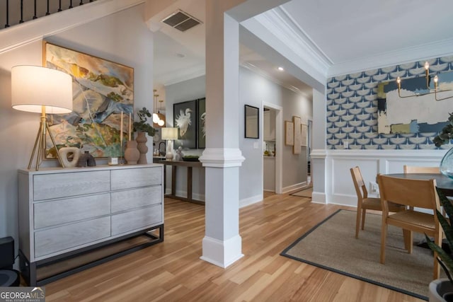 interior space with decorative columns, visible vents, ornamental molding, wainscoting, and wood finished floors