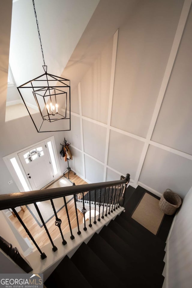 staircase featuring wood finished floors and an inviting chandelier