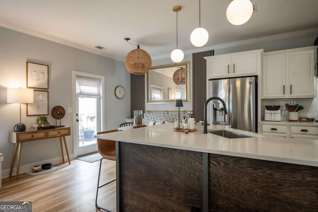 kitchen with crown molding, light countertops, a sink, and stainless steel refrigerator with ice dispenser