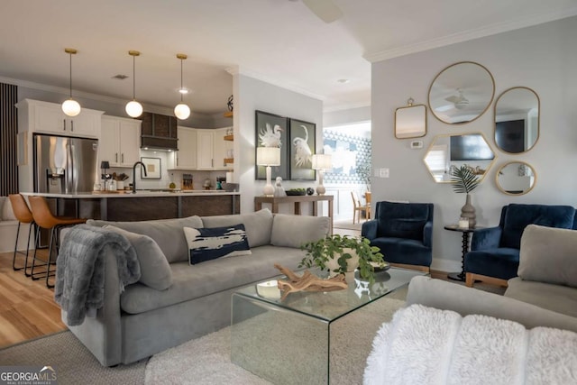 living area with light wood-type flooring and ornamental molding