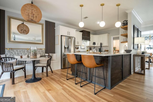 kitchen with light countertops, ornamental molding, light wood-type flooring, and stainless steel fridge with ice dispenser