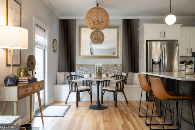 dining area with crown molding and light wood-style floors