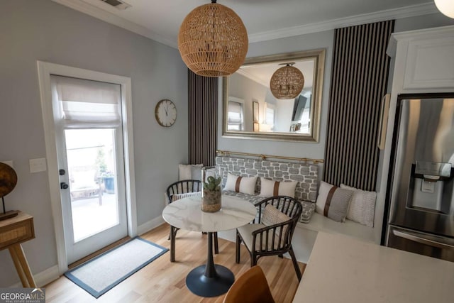 dining space with light wood-type flooring, an inviting chandelier, baseboards, and crown molding