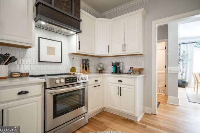 kitchen with light countertops, white cabinets, light wood-type flooring, premium range hood, and stainless steel electric range