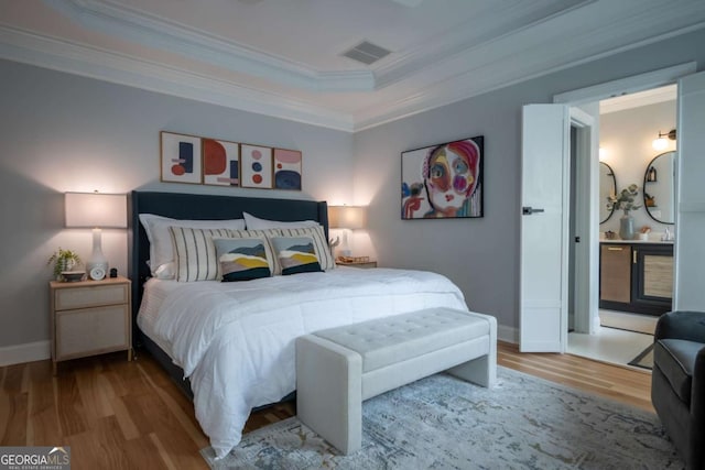 bedroom featuring baseboards, wood finished floors, visible vents, and crown molding