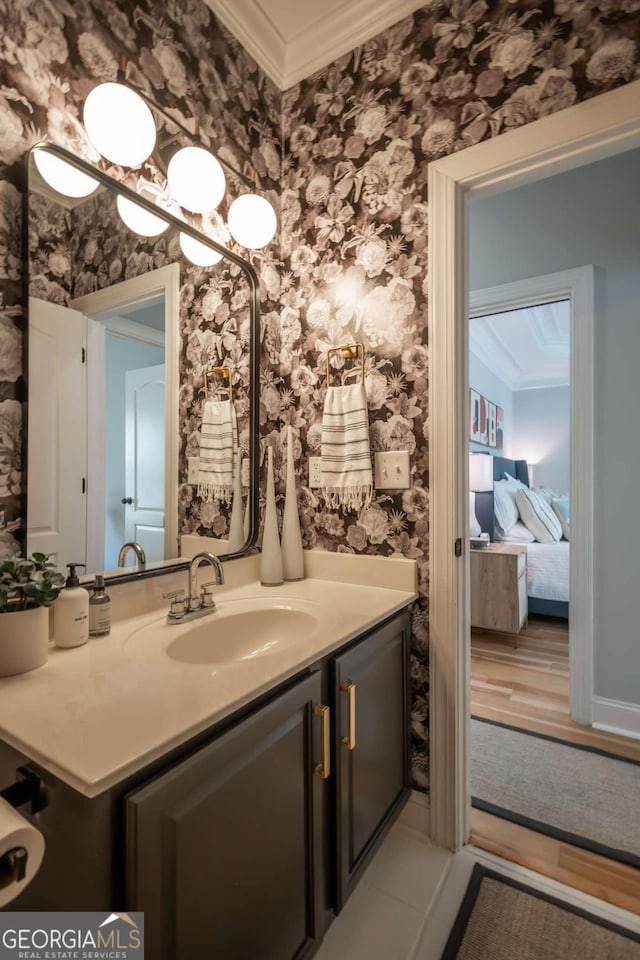 ensuite bathroom featuring ensuite bathroom, ornamental molding, vanity, and wallpapered walls