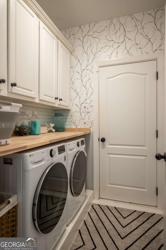 laundry room with washer and clothes dryer, cabinet space, and wallpapered walls