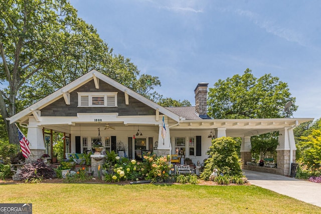 craftsman inspired home with driveway, ceiling fan, a chimney, covered porch, and a front yard