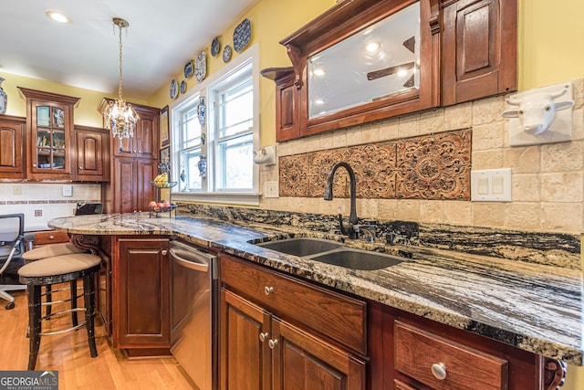 kitchen featuring stainless steel dishwasher, light wood-style floors, glass insert cabinets, a sink, and dark stone counters