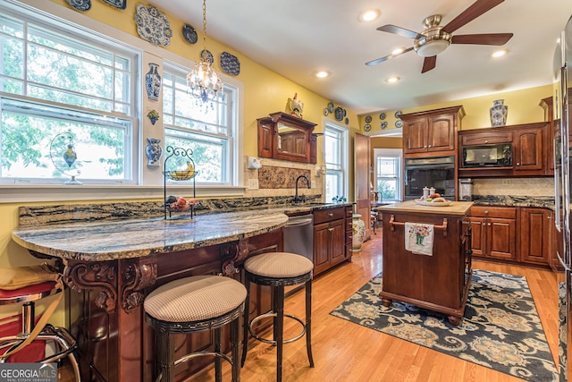 kitchen featuring black microwave, stainless steel dishwasher, light wood finished floors, and oven