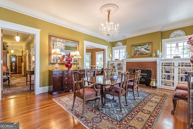 dining room featuring crown molding, wood-type flooring, a chandelier, and plenty of natural light