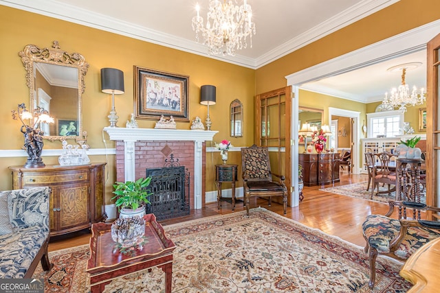 living area featuring a brick fireplace, crown molding, a chandelier, and wood finished floors