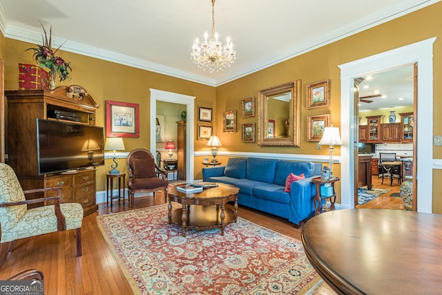 living room featuring baseboards, hardwood / wood-style floors, an inviting chandelier, and crown molding