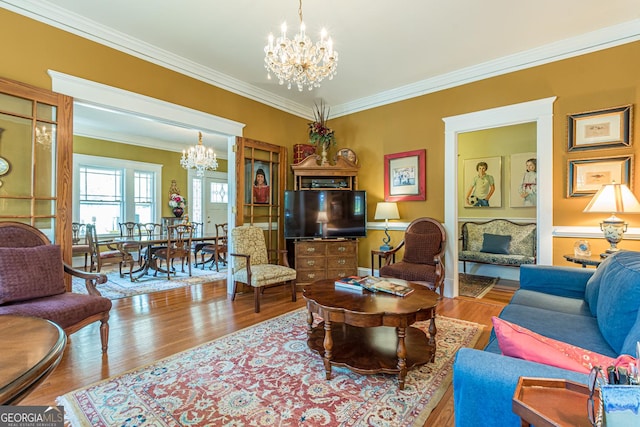 living area featuring ornamental molding, a notable chandelier, and wood finished floors