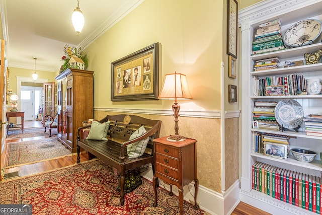 interior space with wainscoting, wood finished floors, visible vents, and crown molding