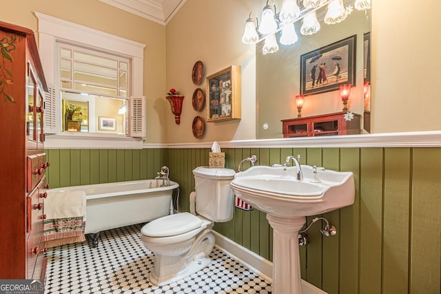 bathroom featuring a wainscoted wall, a freestanding tub, toilet, and crown molding