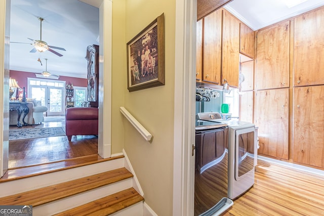 hall with light wood finished floors, baseboards, stairs, crown molding, and washer and dryer