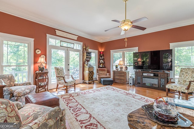 living area with ceiling fan, ornamental molding, wood finished floors, and french doors