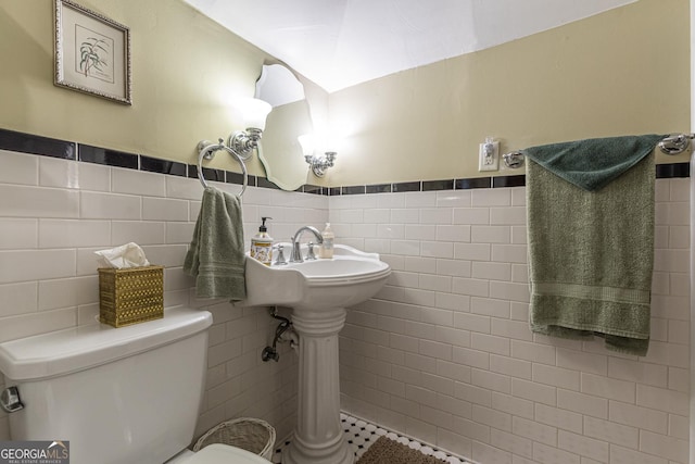 bathroom featuring wainscoting, tile walls, and toilet