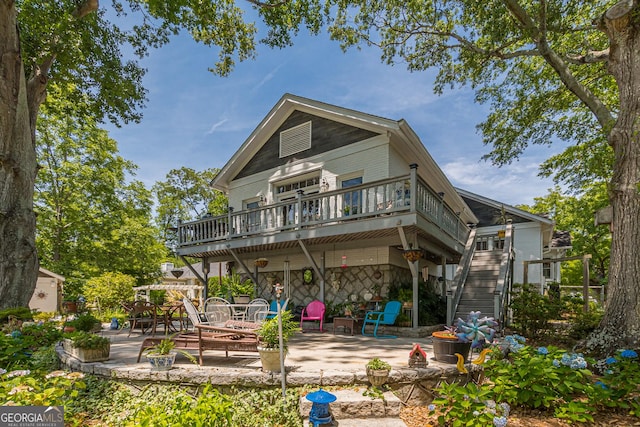 back of property with stone siding, stairs, a deck, and a patio